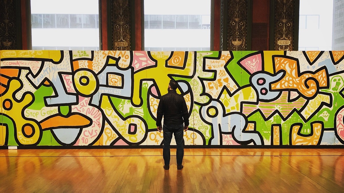 Un visitatore ammira un quadro di Keith Haring